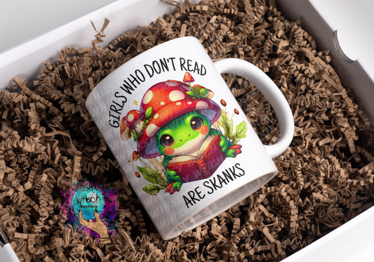 White ceramic mug with kawaii frog reading under red mushroom; bold bookish quote
Close-up of frog and toadstool illustration on funny book lover mug