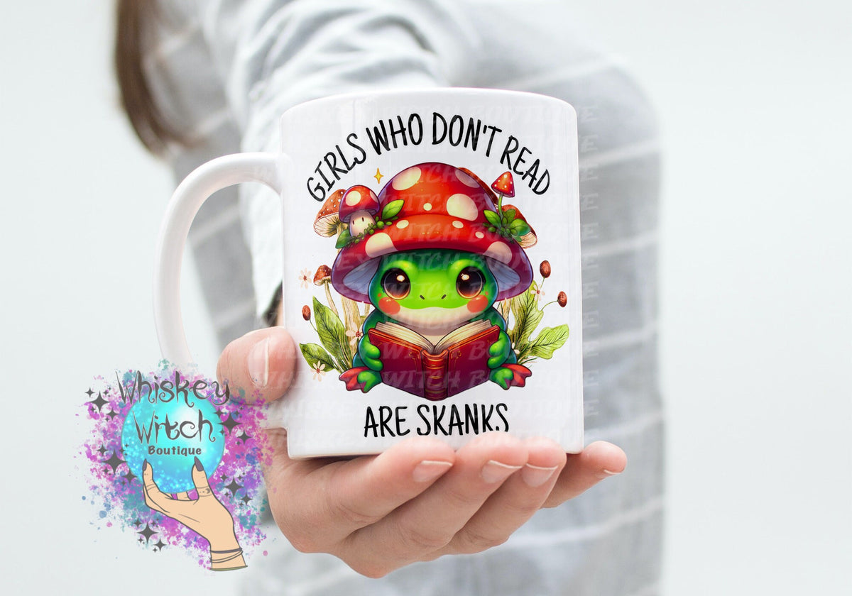 White ceramic mug with kawaii frog reading under red mushroom; bold bookish quote
Close-up of frog and toadstool illustration on funny book lover mug