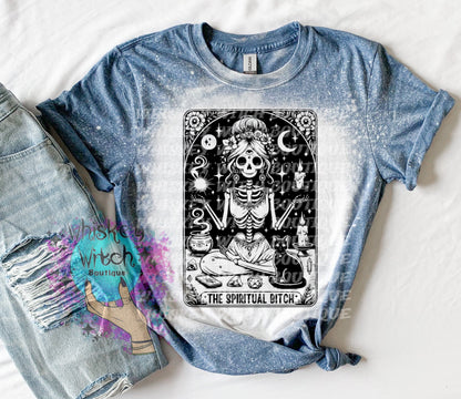 A bleached indigo  blue t-shirt with a black and white illustration of a skeleton woman with a cat and the text "The Spiritual Bitch".
