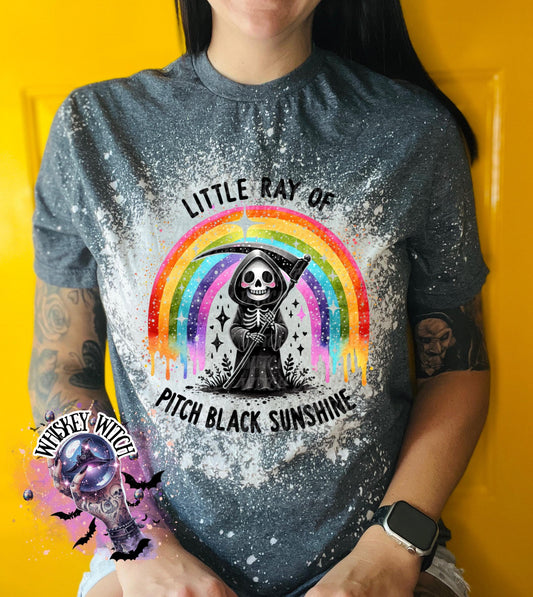 : Gray t-shirt with a colorful rainbow and a Grim Reaper graphic. The text on the shirt reads "Little Ray of Pitch Black Sunshine". The shirt has a bleached, distressed look.