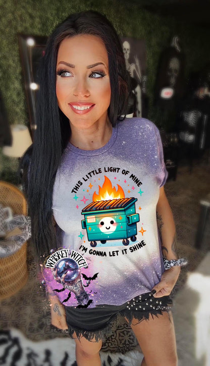 Purple  t-shirt with a bleach-splattered design featuring a cartoon dumpster on fire with the text "This little light of mine I'm gonna let it shine".