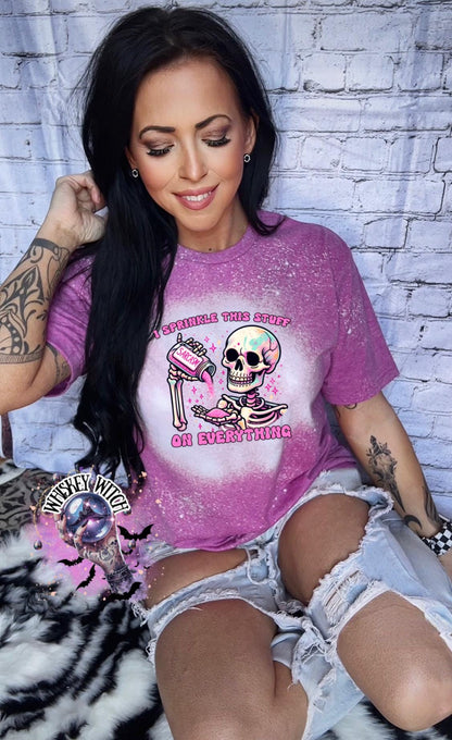 A Berry pink  T shirt with bleach splattered design with a colorful skeleton holding a pouring a salt shaker that has the work ‘sarcasm’ on it with the words on the design ‘ I sprinkle this stuff on everything’