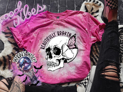 Pink bleached t-shirt with a white skull and butterfly graphic. The text "Beautifully Broken" is printed above the skull.