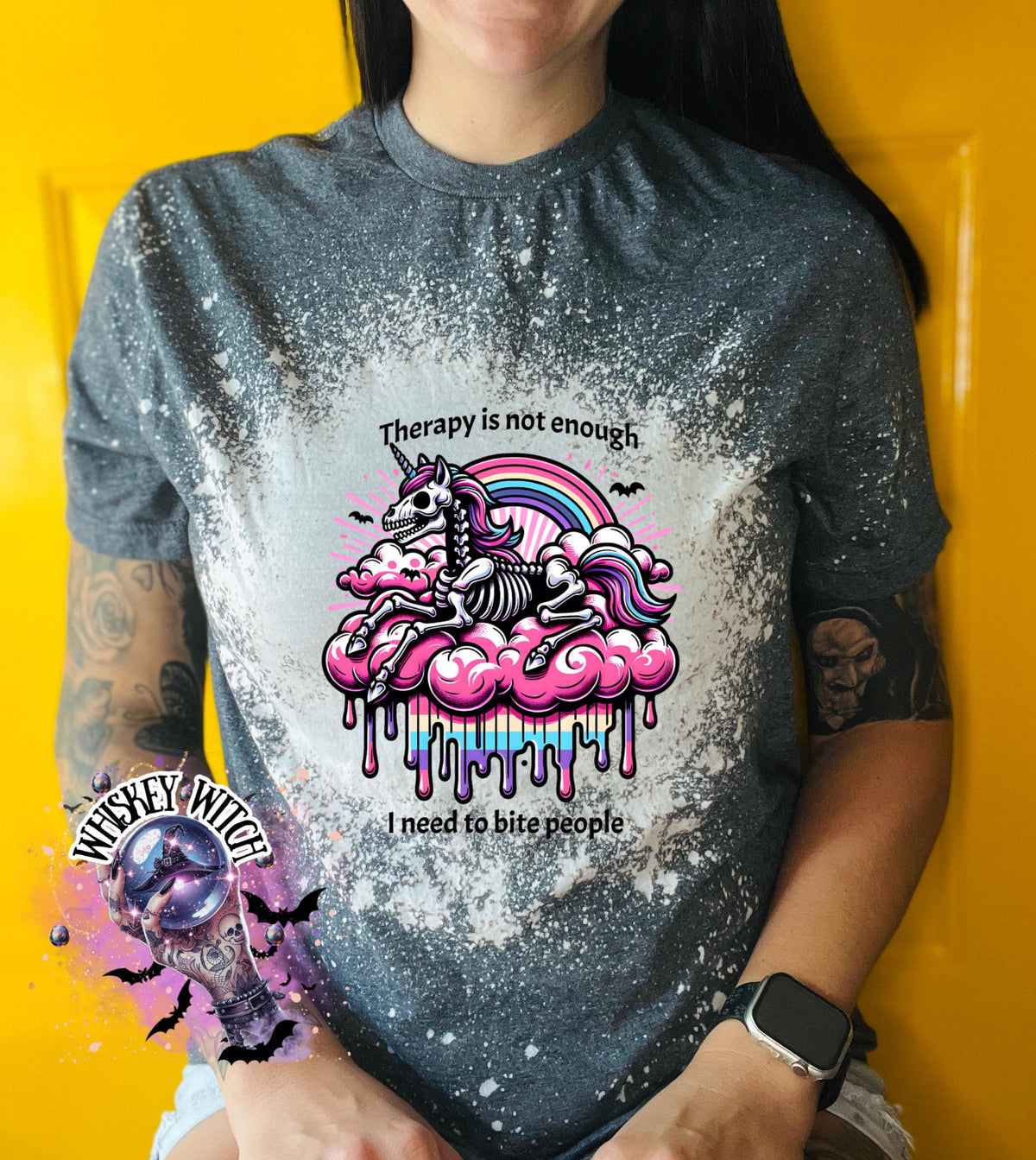 A gre and bleached design T shirt with a skeleton unicorn and a rainbow with a dripping colored cloud with the words “Therapy is not enough, I need to bite people.”