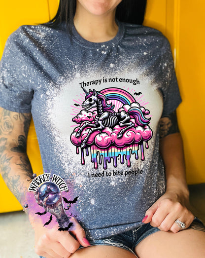 A navy blue  and bleached design T shirt with a skeleton unicorn and a rainbow with a dripping colored cloud with the words “Therapy is not enough, I need to bite people.”