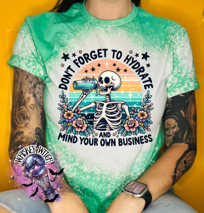 A green and white bleached t-shirt with a skeleton drinking from a bottle and the text "Don't forget to hydrate and mind your own business".