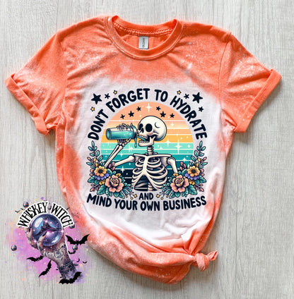 A Orange and white bleached t-shirt with a skeleton drinking from a bottle and the text "Don't forget to hydrate and mind your own business".