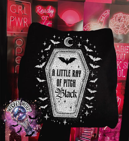 Black sweatshirt featuring a coffin design with bats, stars, and the text "A Little Ray of Pitch Black." The design is in white and gray, with a crescent moon at the top. The sweatshirt has a round neckline.