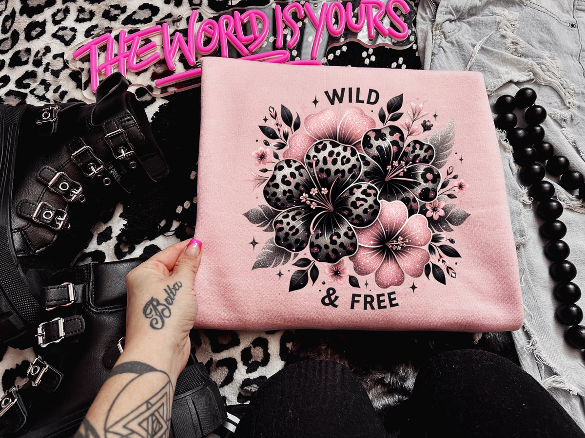 Light pink unisex sweatshirt with ‘Wild & Free’ leopard floral hibiscus graphic in black and pink