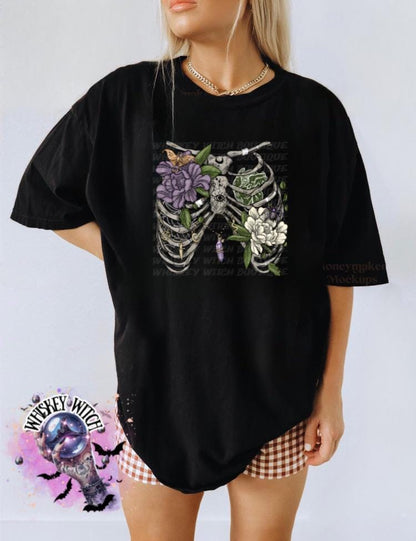 Black unisex t-shirt with floral rib cage skeleton graphic—lavender and white flowers, leaves, butterfly.