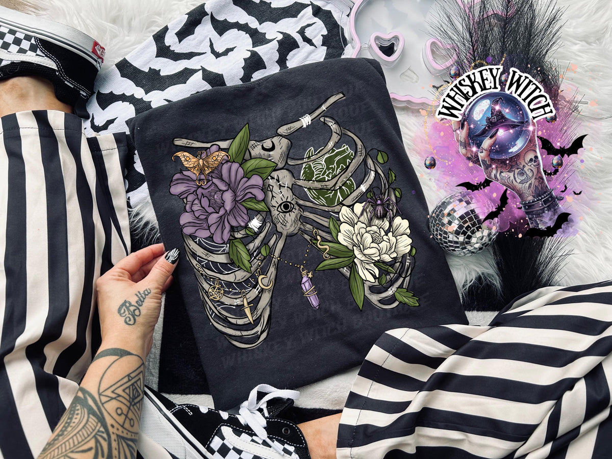 Black unisex t-shirt with floral rib cage skeleton graphic—lavender and white flowers, leaves, butterfly.