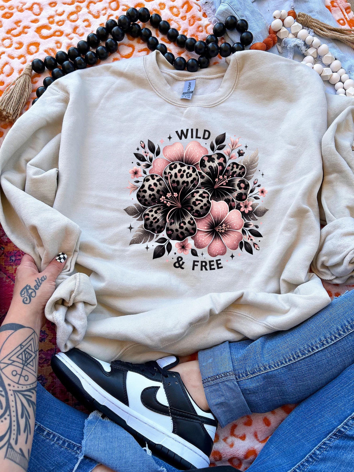 Light pink unisex sweatshirt with ‘Wild & Free’ leopard floral hibiscus graphic in black and pink