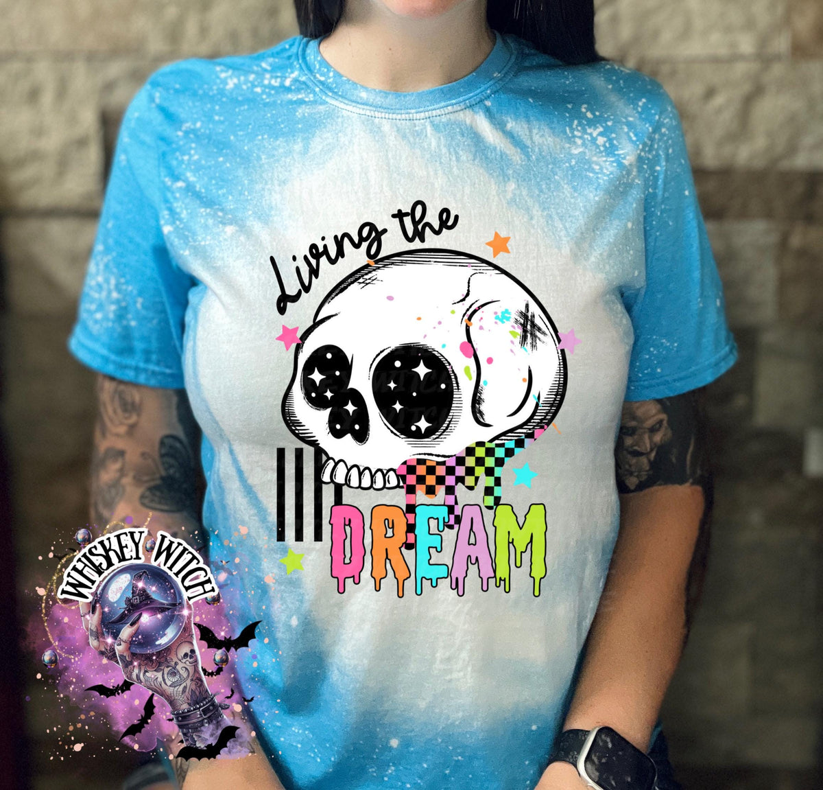 Hand-bleached saphire graphic tee featuring a skull illustration, small stars, and the words “Living the Dream” with rainbow drip lettering.