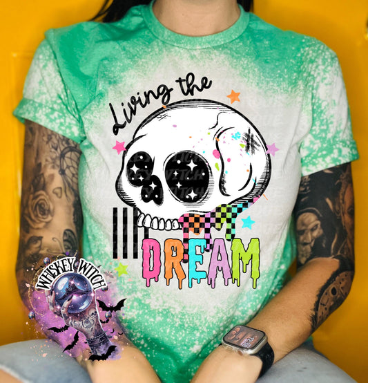 Hand-bleached Irish Green graphic tee featuring a skull illustration, small stars, and the words “Living the Dream” with rainbow drip lettering.