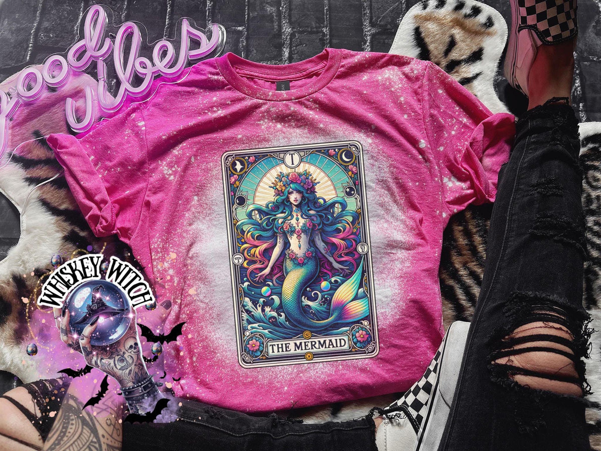 Mystical mermaid tarot card graphic centered on a Heliconia pink bleach-dyed shirt, photographed with neon pink sign and cozy background props.