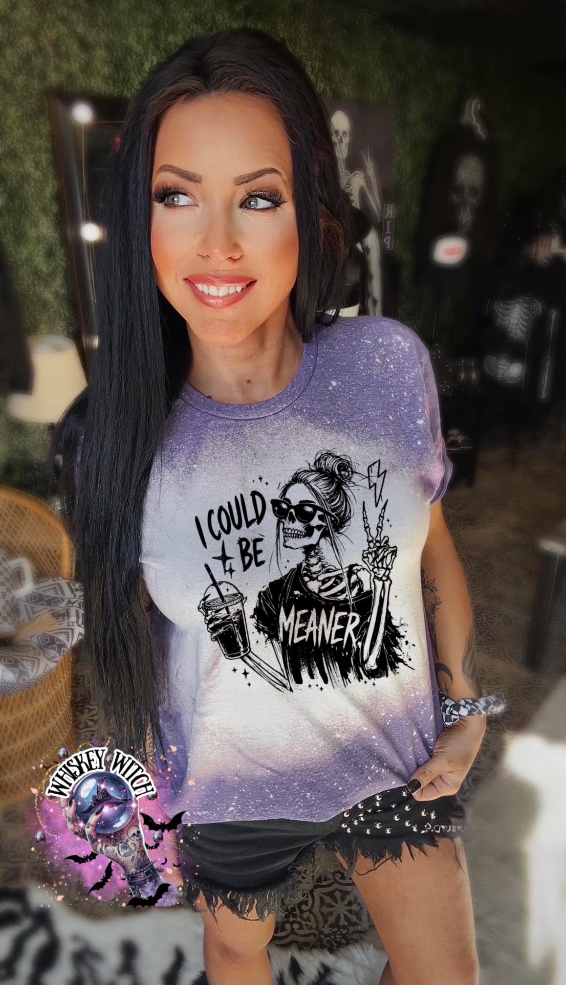 A purple and white tie-dye t-shirt with the text "I COULD BE MEANER" and a skeleton graphic. The skeleton is wearing sunglasses and holding a coffee cup and making a peace sign. The shirt is part of a clothing collection.