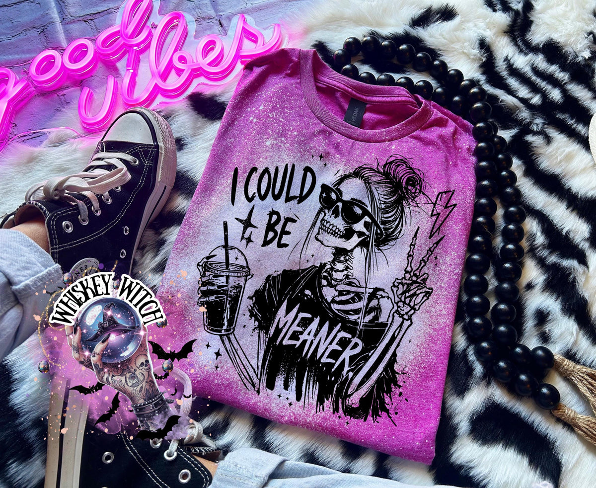 A Berry pink t-shirt with bleach white splatter effect with a graphic of a skeleton wearing sunglasses, holding a drink, and making a peace sign. The text on the shirt reads "I COULD BE MEANER.”