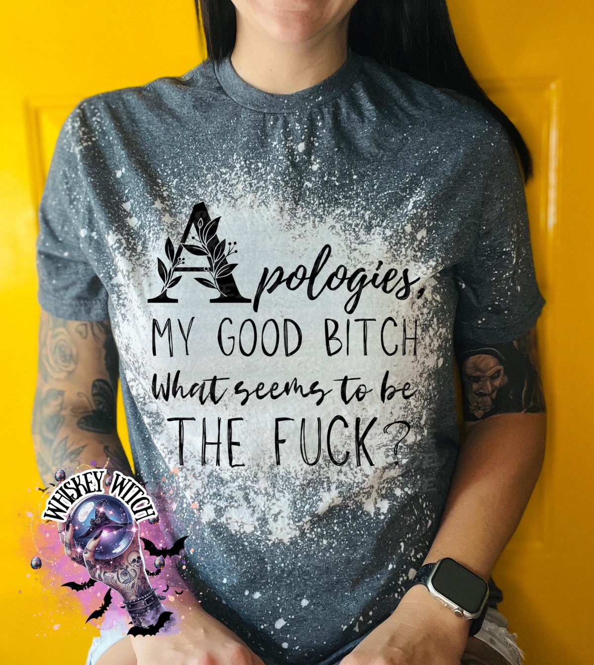 A grey  t-shirt with a bleached design and the text "Apologies, MY GOOD BITCH What seems to be THE FUCK?". The shirt has a round neck and short sleeves.