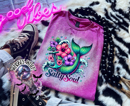 A Berry pink  t-shirt with a bleach splatter effect. The shirt features a colorful graphic of a mermaid tail, anchor, flowers, and the text "Salty Soul". The mermaid tail is green and blue.