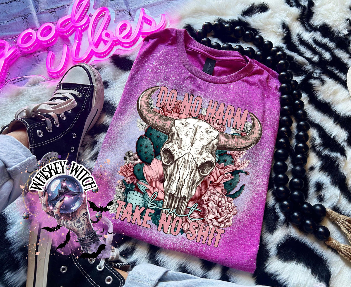 Berry pink t-shirt with a bleached effect, featuring a cow skull graphic with pink horns, surrounded by pink flowers and cacti. The text "DO NO HARM" arches above the skull, with "but TAKE NO SHIT" below.