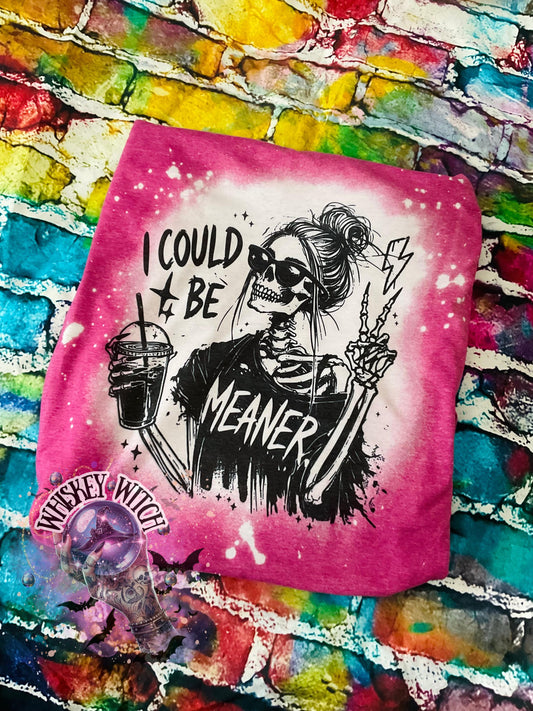 A pink t-shirt with bleach white splatter effect with a graphic of a skeleton wearing sunglasses, holding a drink, and making a peace sign. The text on the shirt reads "I COULD BE MEANER.”