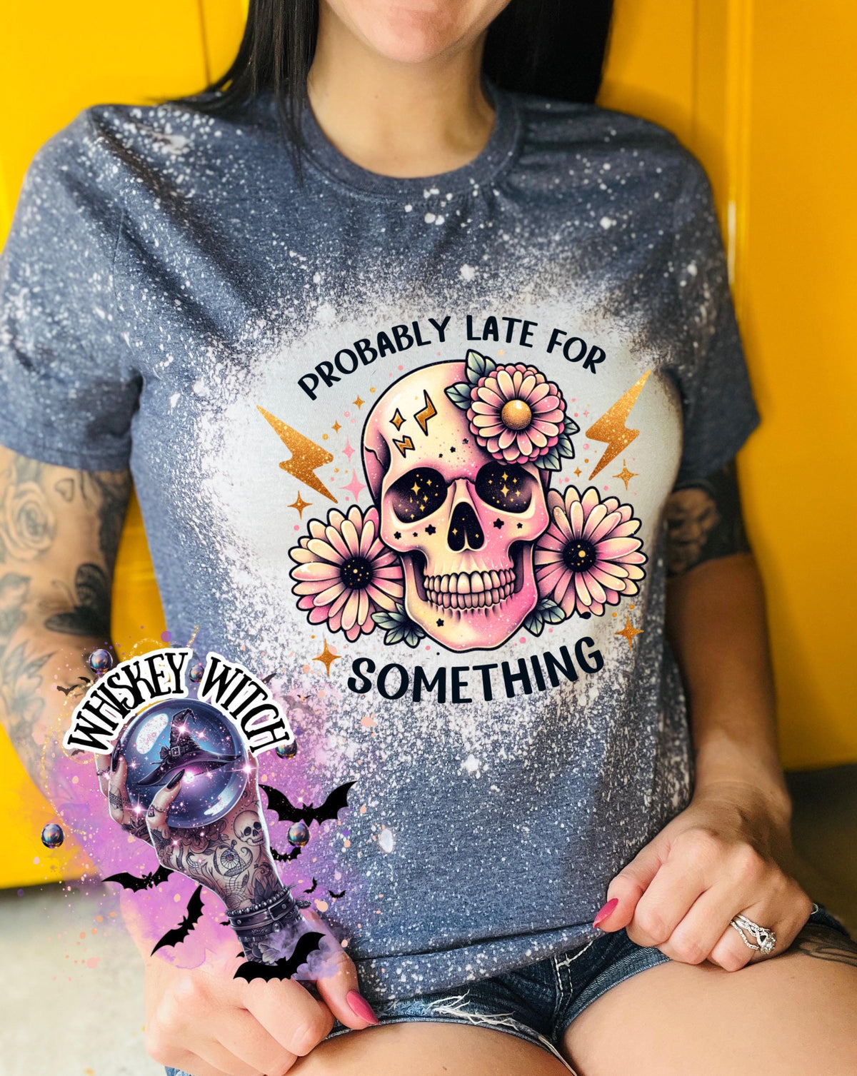 A navy blue  t-shirt with a bleached effect featuring a skull with flowers and the text "Probably Late For Something" in gold glitter.