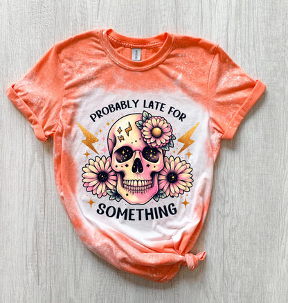 A Orange  t-shirt with a bleached effect featuring a skull with flowers and the text "Probably Late For Something" in gold glitter.