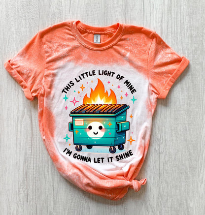 Orange t-shirt with a bleach-splattered design featuring a cartoon dumpster on fire with the text "This little light of mine I'm gonna let it shine".