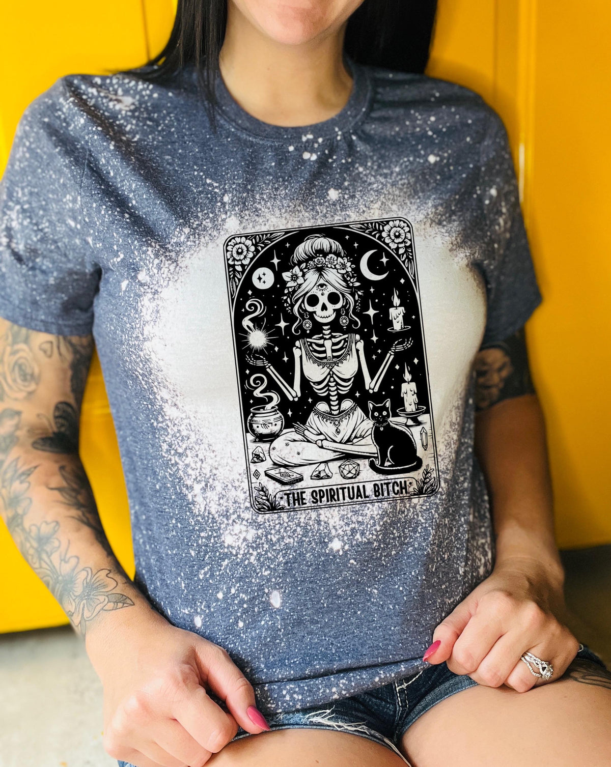 A bleached navy blue t-shirt with a black and white illustration of a skeleton woman with a cat and the text "The Spiritual Bitch".