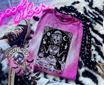 A bleached Berry pink  t-shirt with a black and white illustration of a skeleton woman with a cat and the text "The Spiritual Bitch".