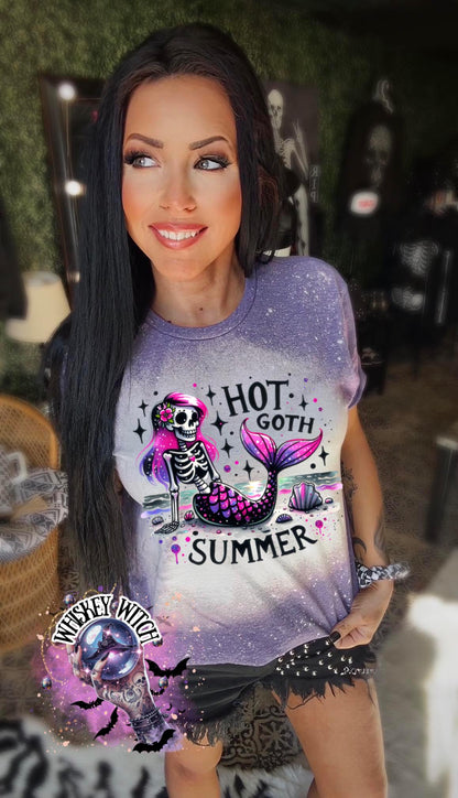 A purple  t-shirt with a bleach-splattered design featuring a pink and purple skeleton mermaid with the text "Hot Goth Summer".