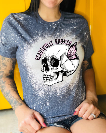 Navy colored  bleached t-shirt with a white skull and butterfly graphic. The text "Beautifully Broken" is printed above the skull.