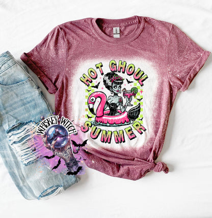 A maroon and bleach splattered effect  t-shirt with a graphic of a zombie woman in a flamingo pool float, holding a cocktail. The text "Hot Ghoul Summer" is printed on the shirt.
