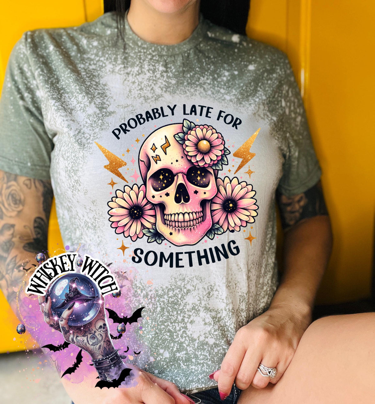 A military green  t-shirt with a bleached effect featuring a skull with flowers and the text "Probably Late For Something" in gold glitter.