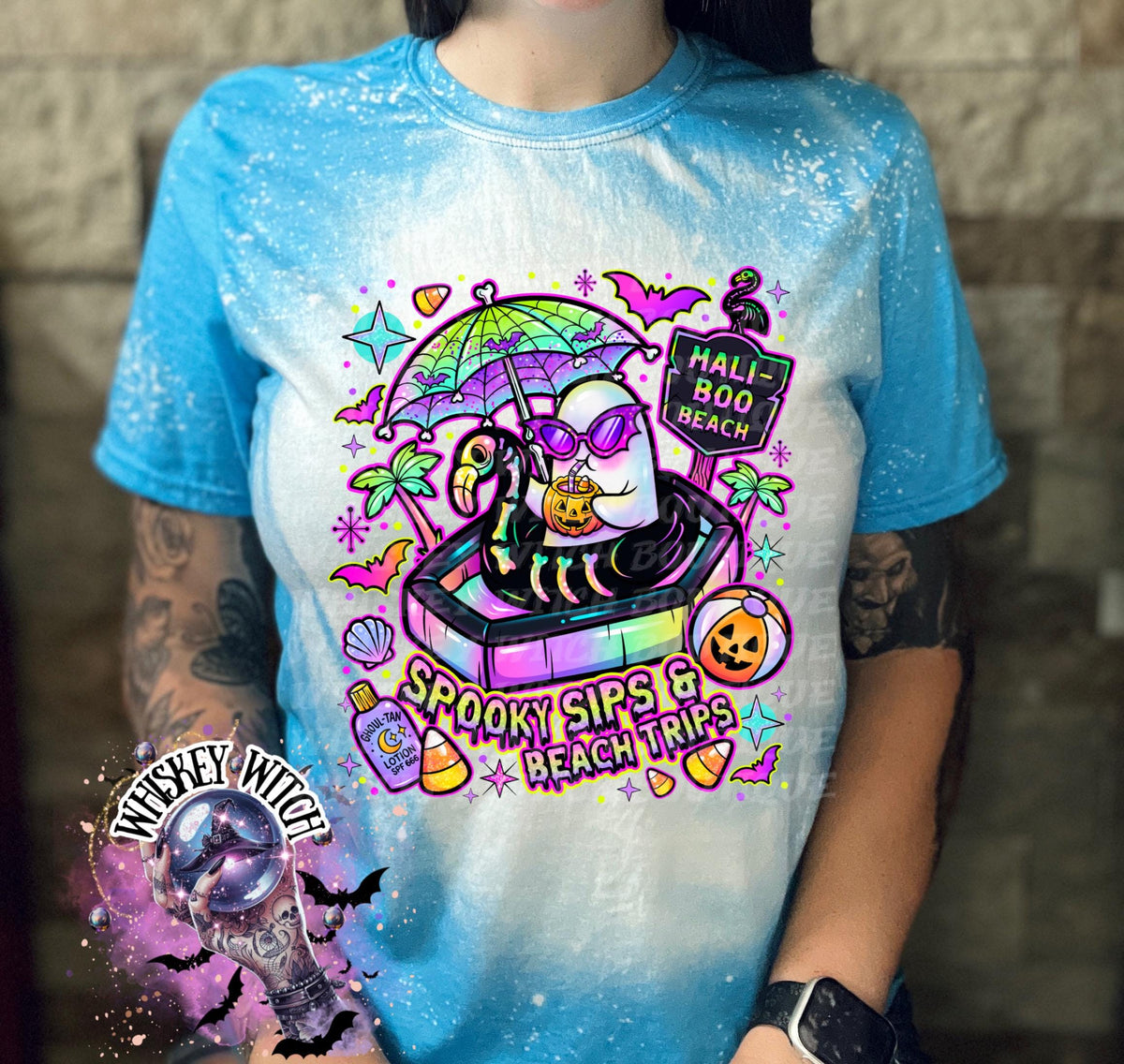 Close-up of spooky beach shirt design with ghost in float, tropical palm trees, bats, candy corn, and neon summer colors.