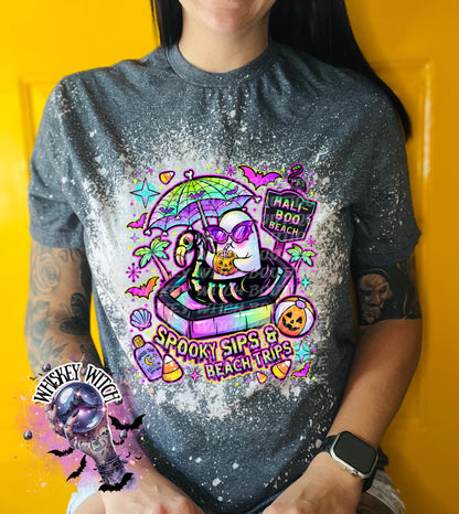 Close-up of spooky beach shirt design with ghost in float, tropical palm trees, bats, candy corn, and neon summer colors.