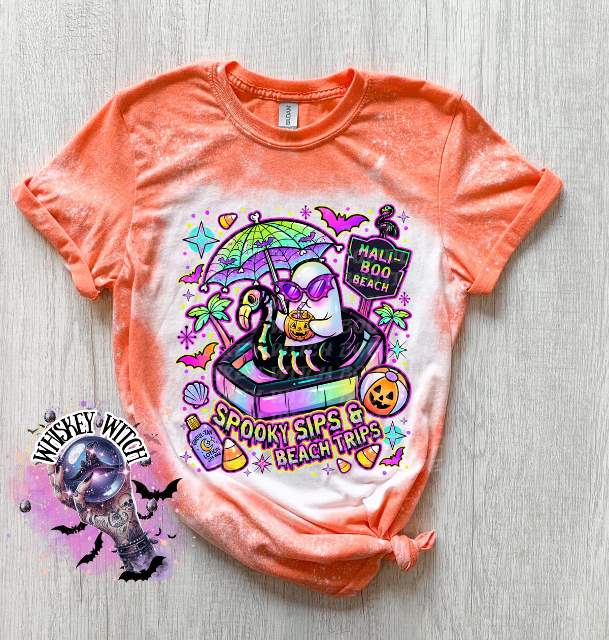 Close-up of spooky beach shirt design with ghost in float, tropical palm trees, bats, candy corn, and neon summer colors.