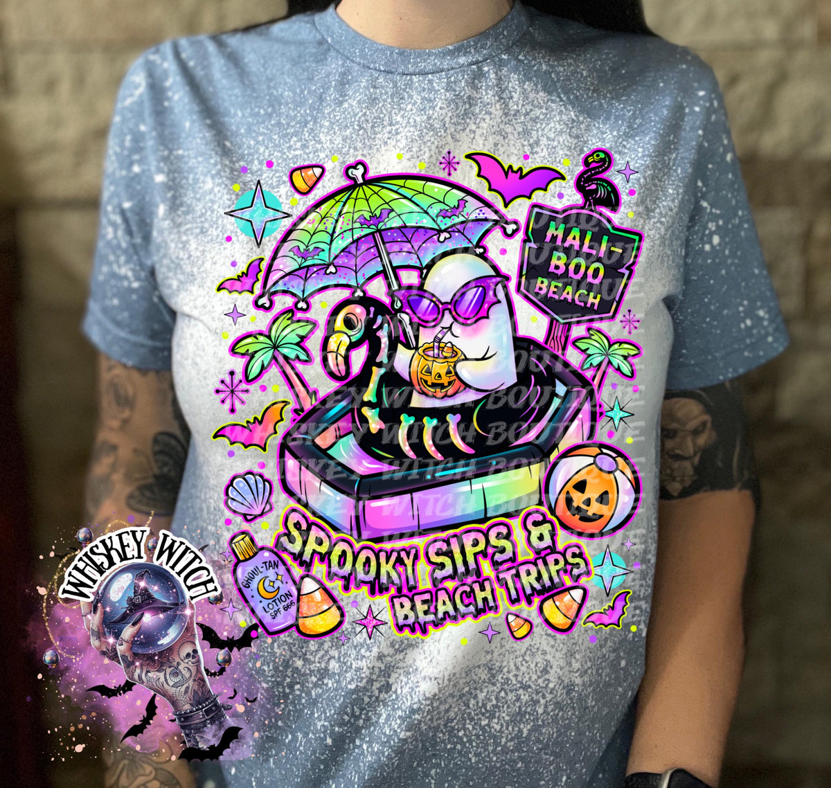 Close-up of spooky beach shirt design with ghost in float, tropical palm trees, bats, candy corn, and neon summer colors.