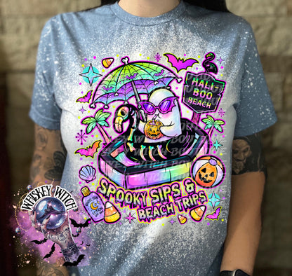 Close-up of spooky beach shirt design with ghost in float, tropical palm trees, bats, candy corn, and neon summer colors.