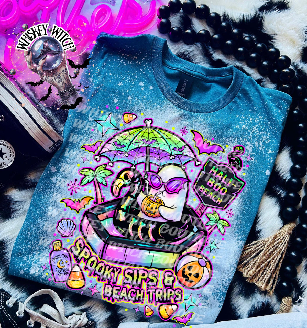 Close-up of spooky beach shirt design with ghost in float, tropical palm trees, bats, candy corn, and neon summer colors.