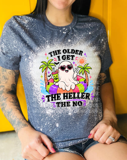 : Dark blue t-shirt with a graphic featuring a ghost wearing sunglasses and a pool float. The text reads "THE OLDER I GET THE HELLER THE NO". The design includes palm trees, a drink, and a sun.
