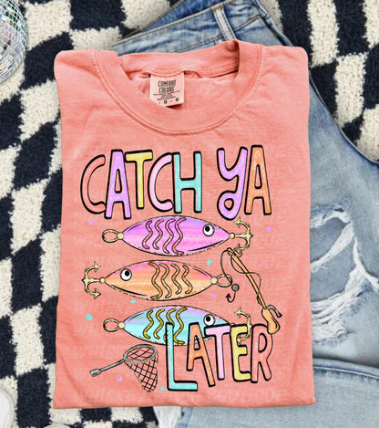 Cute lake day graphic tee with Catch Ya Later text, fishing lures, and a small fishing net design.