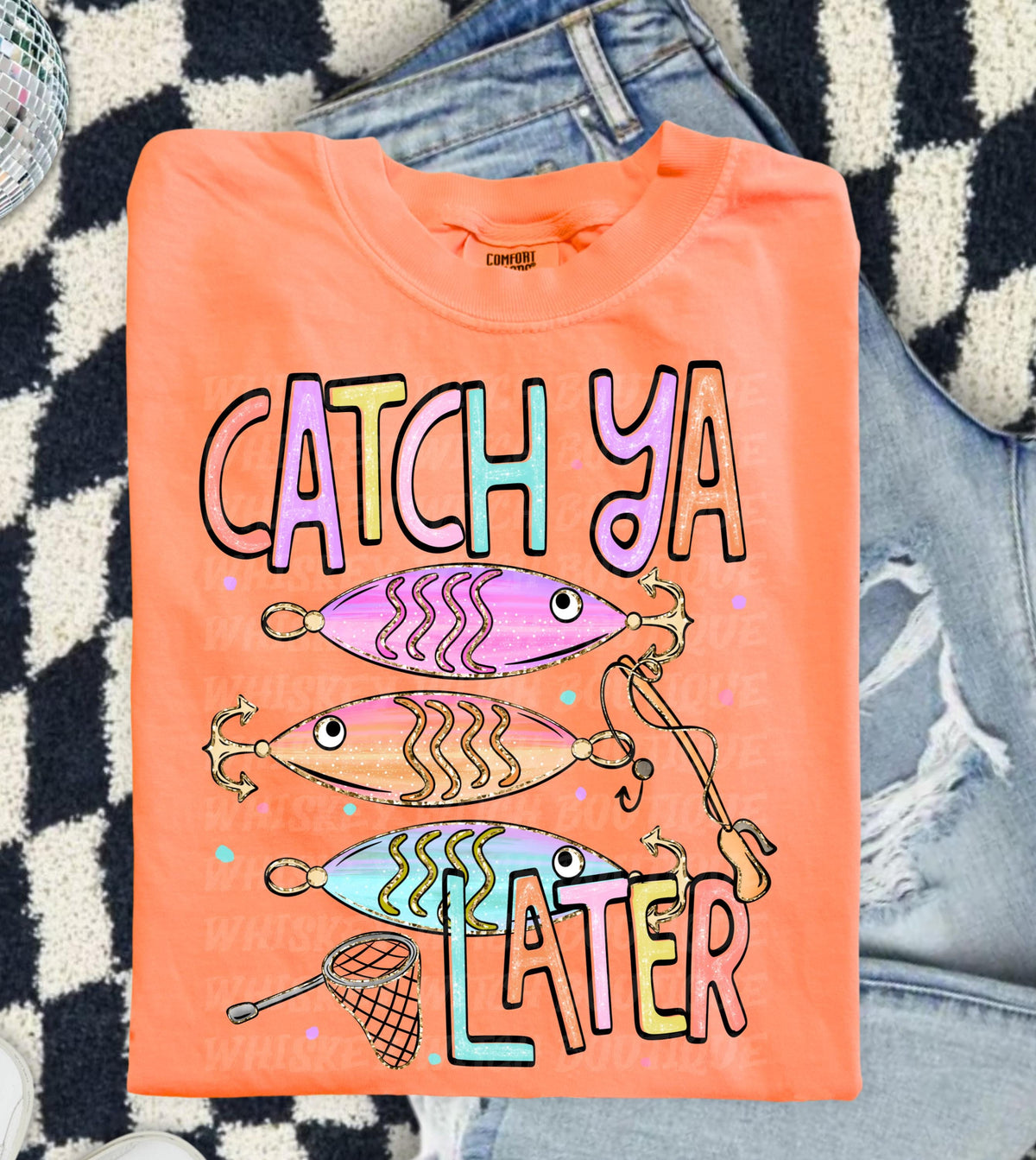 Cute lake day graphic tee with Catch Ya Later text, fishing lures, and a small fishing net design.