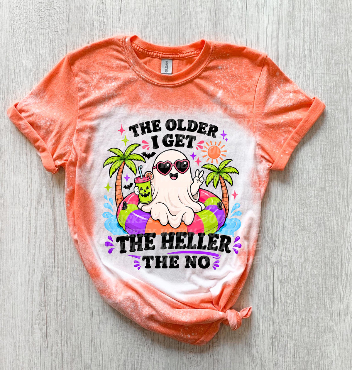 Orange and white tie-dye t-shirt with a graphic of a ghost wearing sunglasses and floating on an inner tube. The text reads "THE OLDER I GET THE HELLER THE NO". The ghost is holding a drink.
