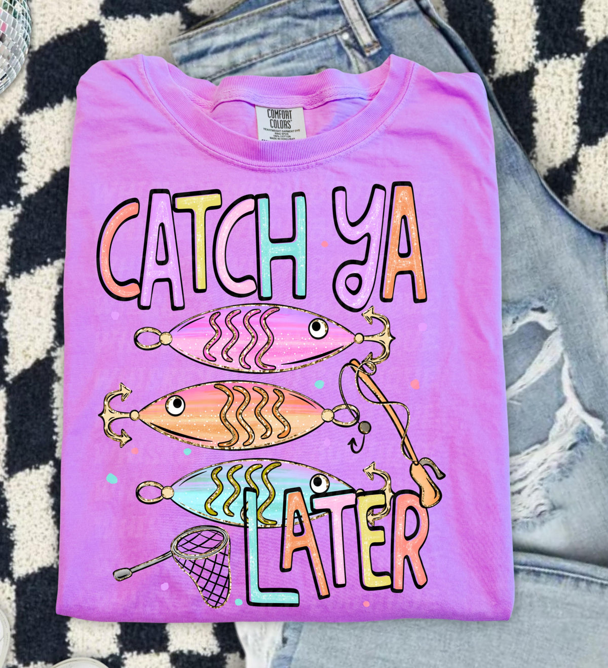 Cute lake day graphic tee with Catch Ya Later text, fishing lures, and a small fishing net design.