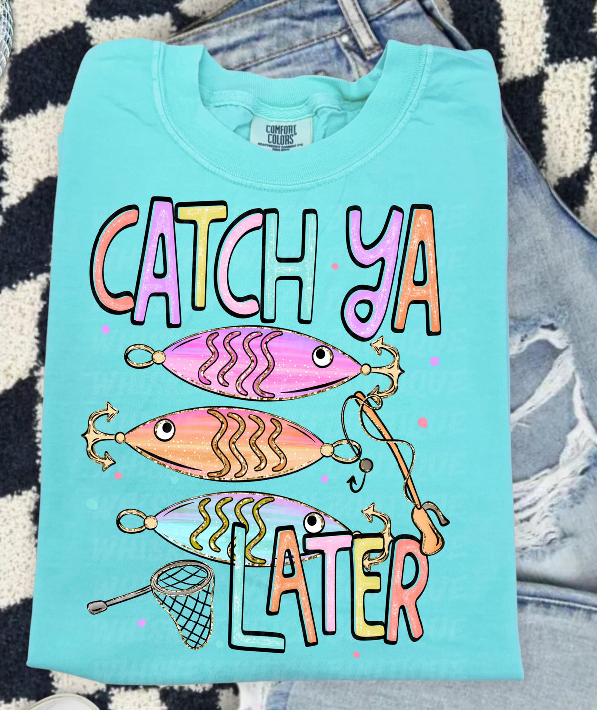 Cute lake day graphic tee with Catch Ya Later text, fishing lures, and a small fishing net design.